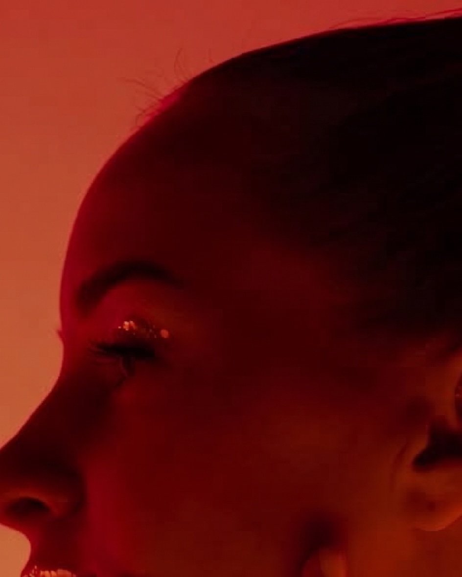 Perfil del rostro de una mujer con los ojos entrecerrados, iluminado por luz roja intensa.